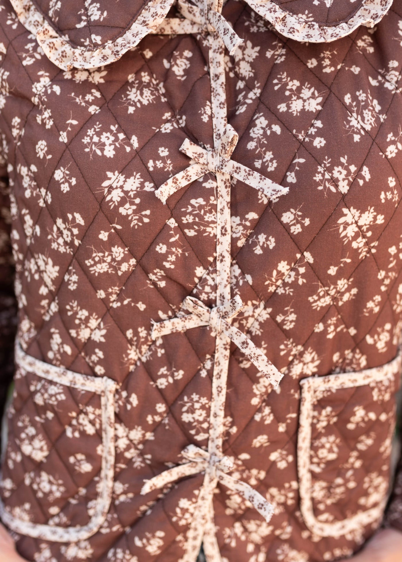 Close up of the quilted fabric and pockets on the ivory and brown floral jacket