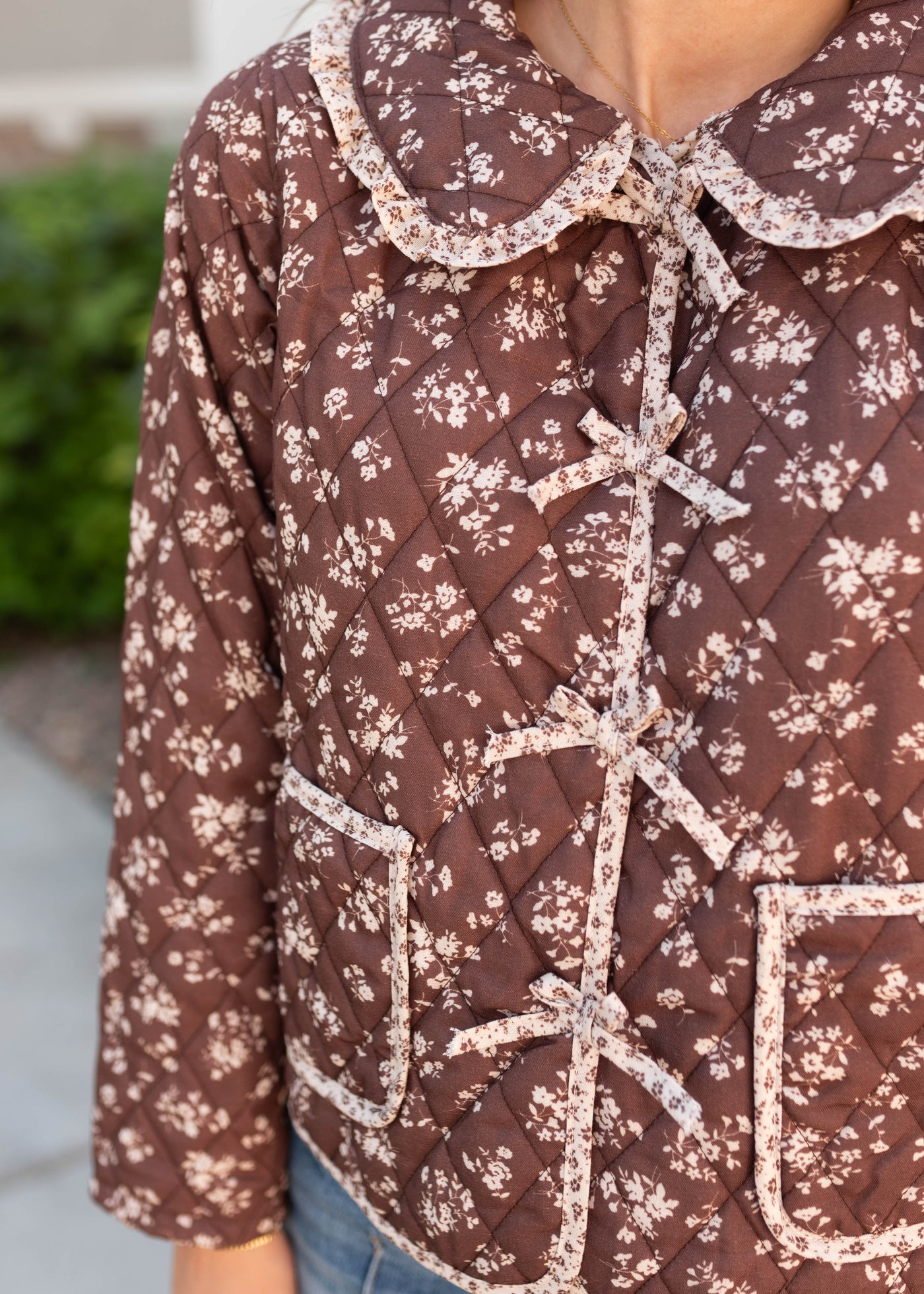 Close up of the bows on the brown floral jacet and round ruffle collar