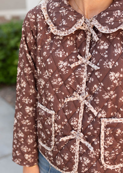 Close up of the bows on the brown floral jacet and round ruffle collar