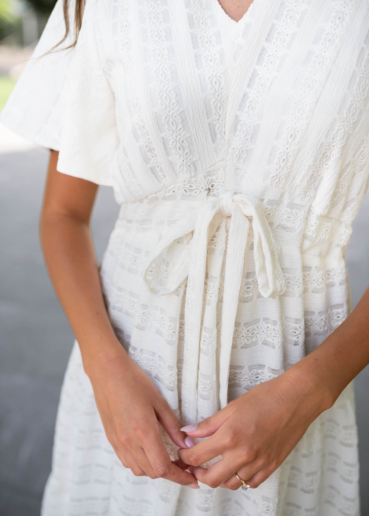 Front view of the tie at the wasit on the ivory textured tie dress