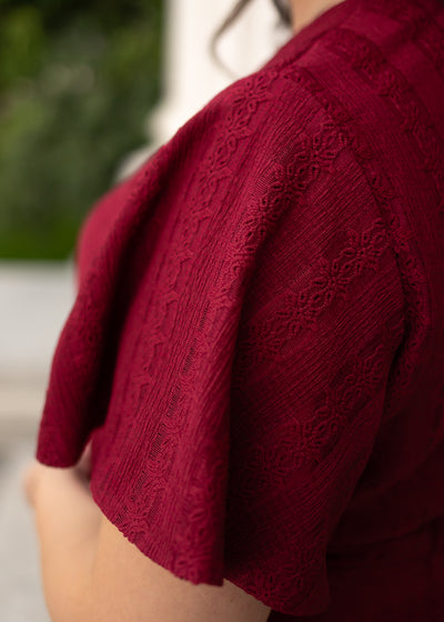 Close up of the sleeve and fabric on the maroon textured tie dress