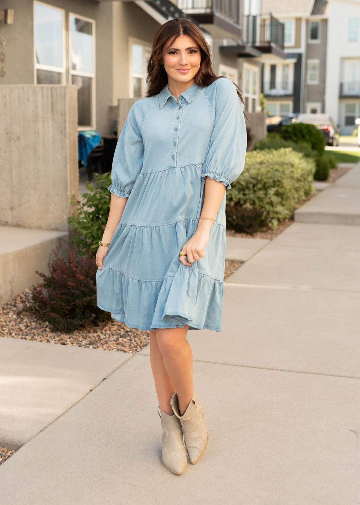 Knee length chambray tiered dress with short sleeves and pockets with button up bodice