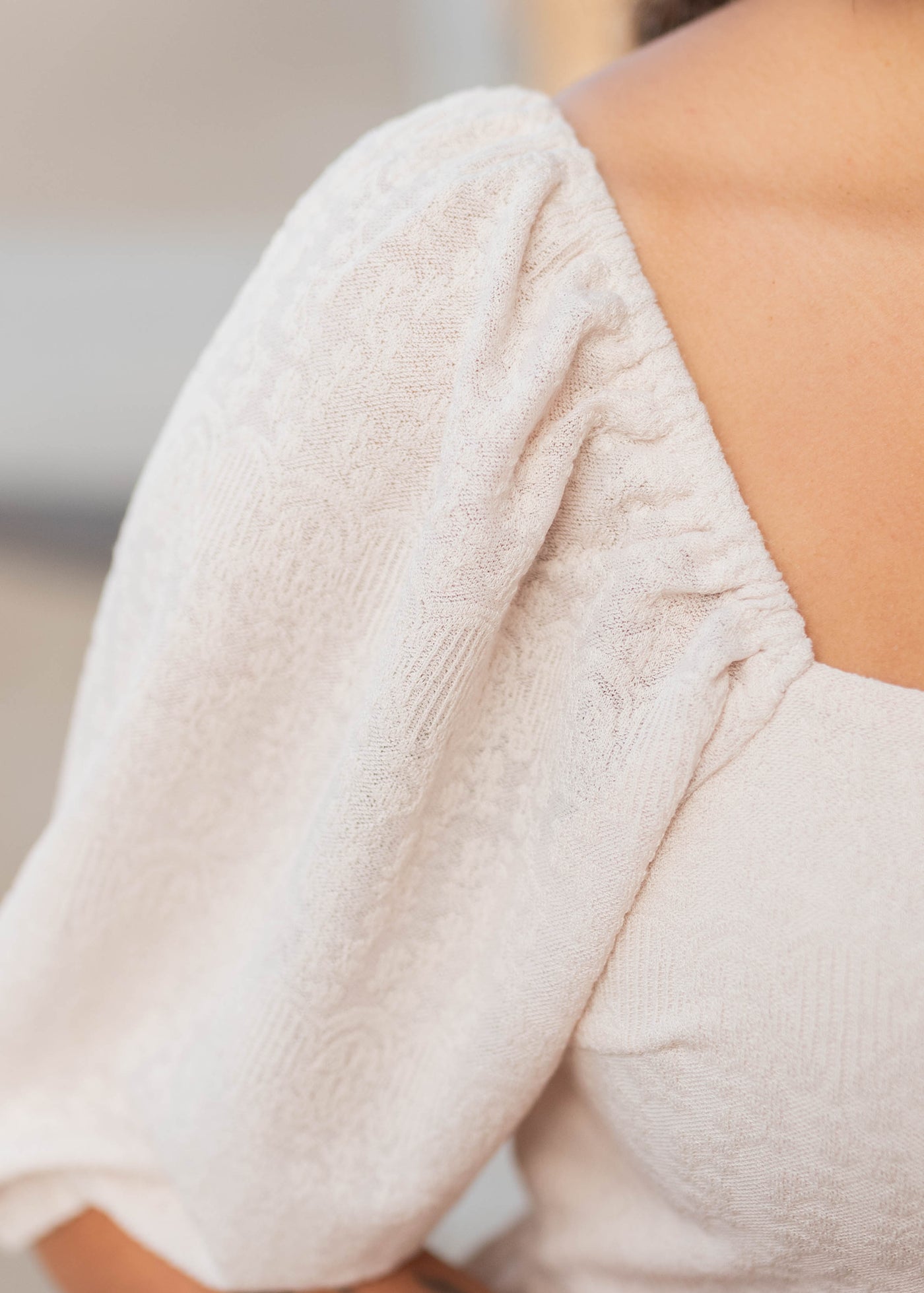 Close up of the fabric and sleeve on the cream square neck dress