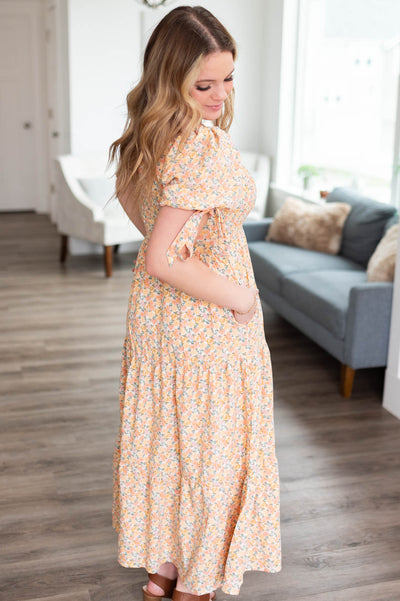Side view of the peach floral dress with pockets and ties on the sleeves