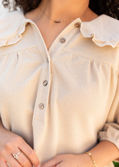 Cloe up of the buttons and fabric on the waffle knit natural collared top
