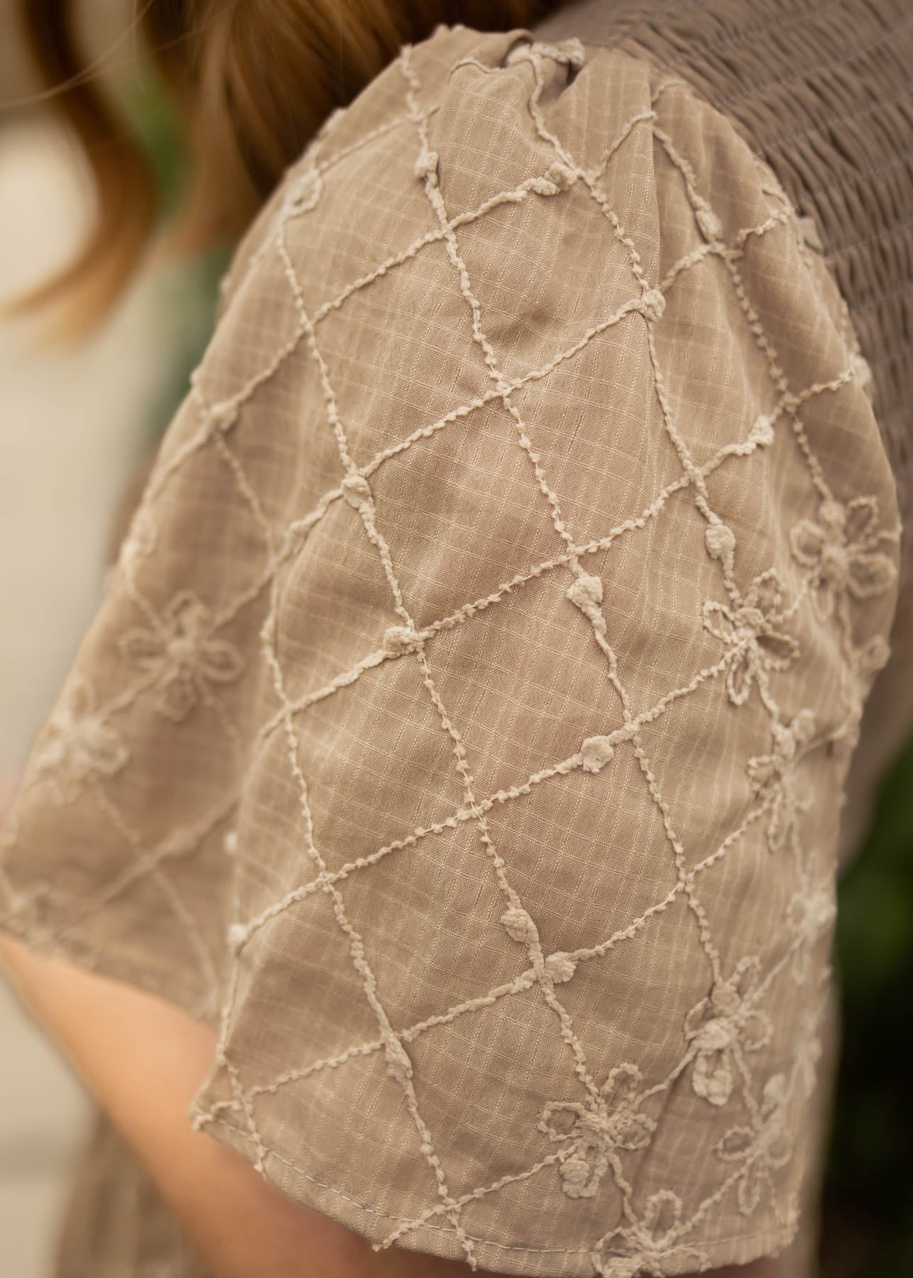 The sleeve of a plus size taupe dress