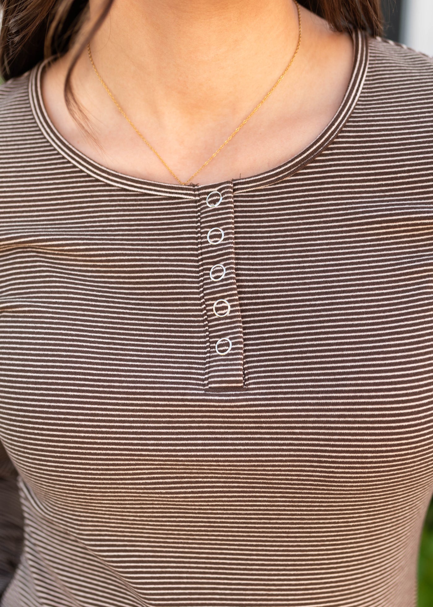 Close up of the snap at the neck on the brown striped top