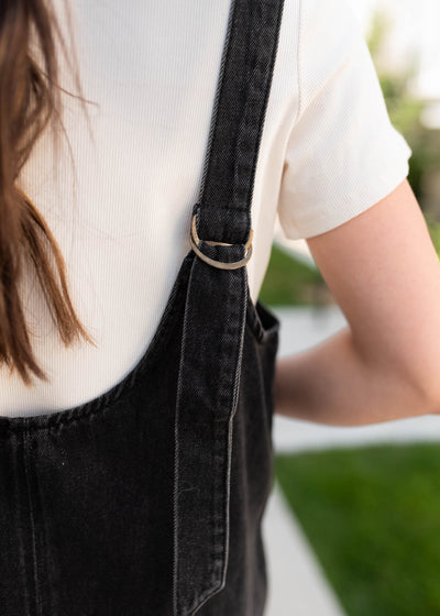 Close up of the adjustable straps on the black dneim overall dress