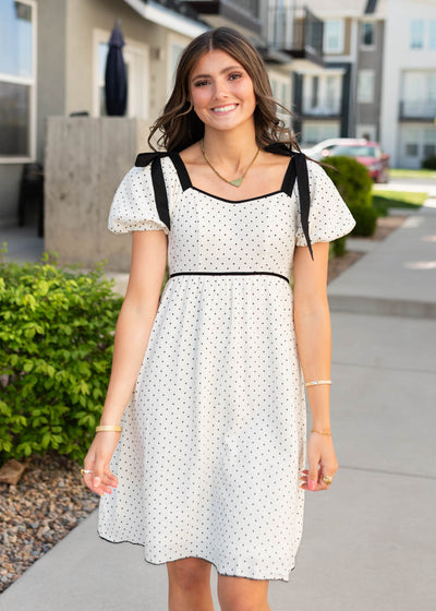 Ivory polka dot dress with black bows on the shoulders and short sleeves