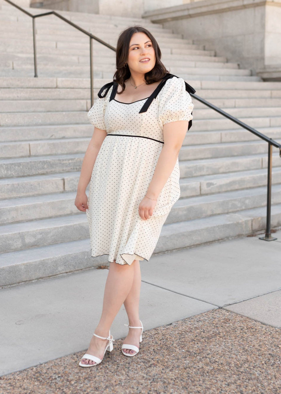 Black bows on the shoulders of the plus size ivory polka dot dress