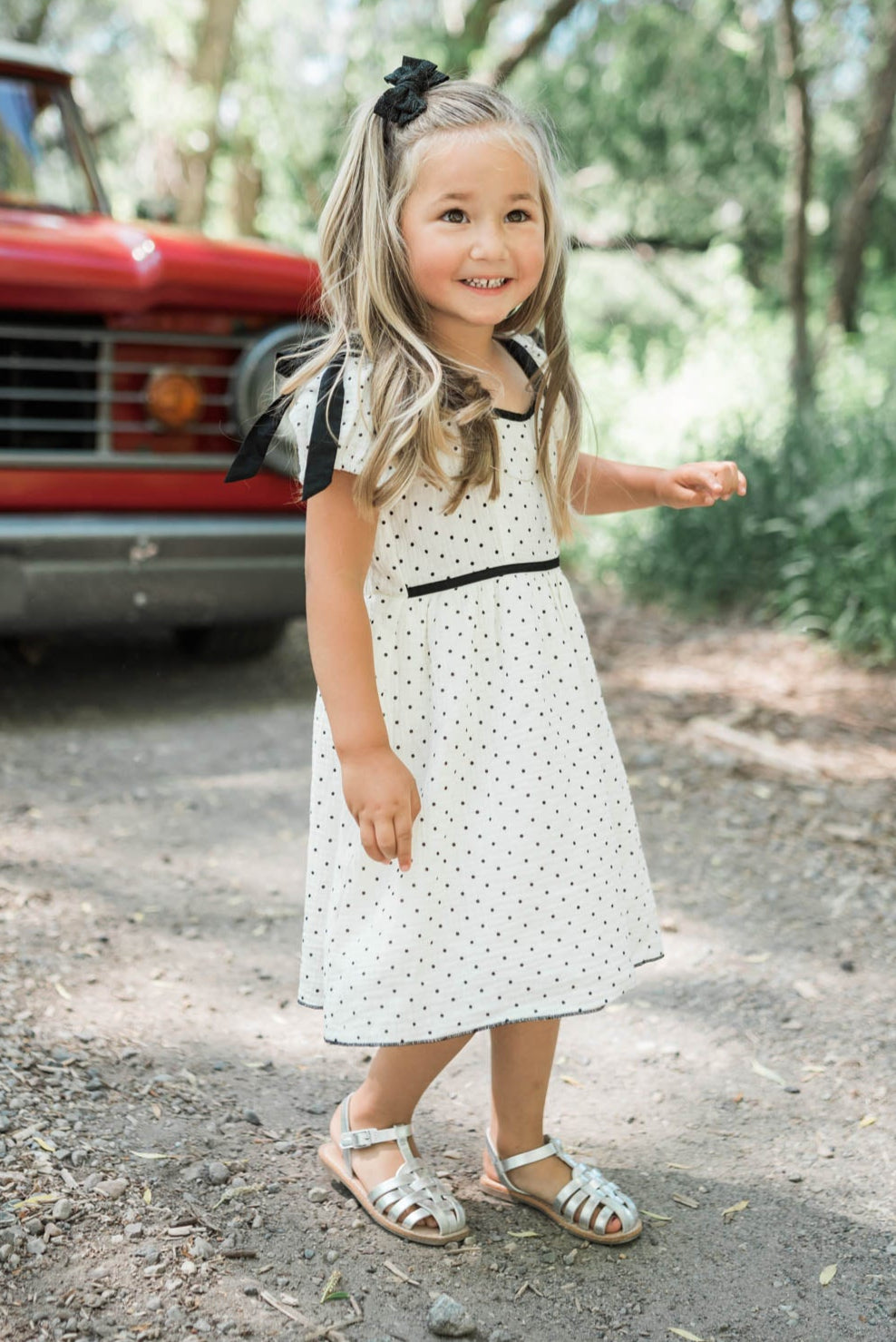 Ivory polka dot little girl dress with black trim at the waist