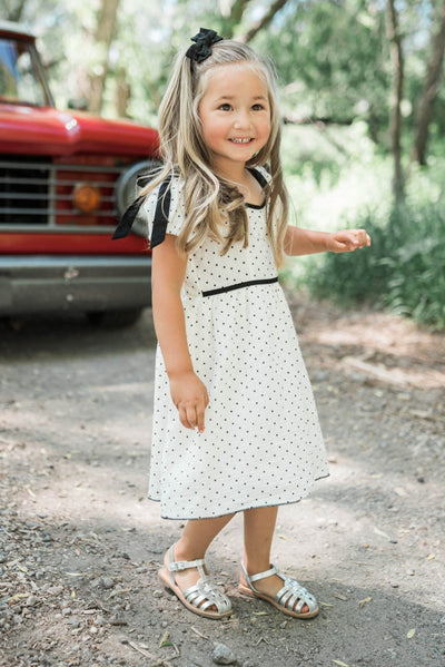 Ivory polka dot little girl dress with black trim at the waist