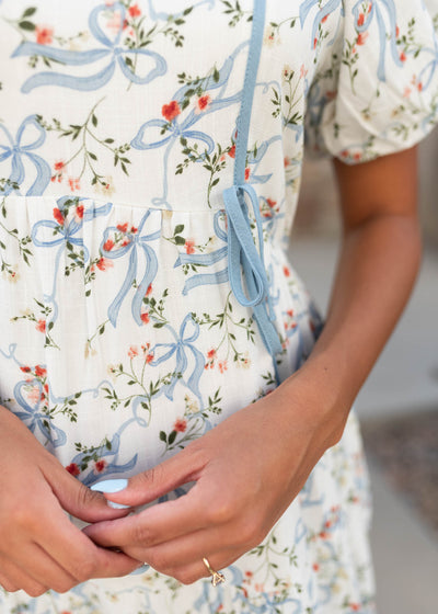 Close up of the fabric and bows on the modest white ribbbon pattern dress
