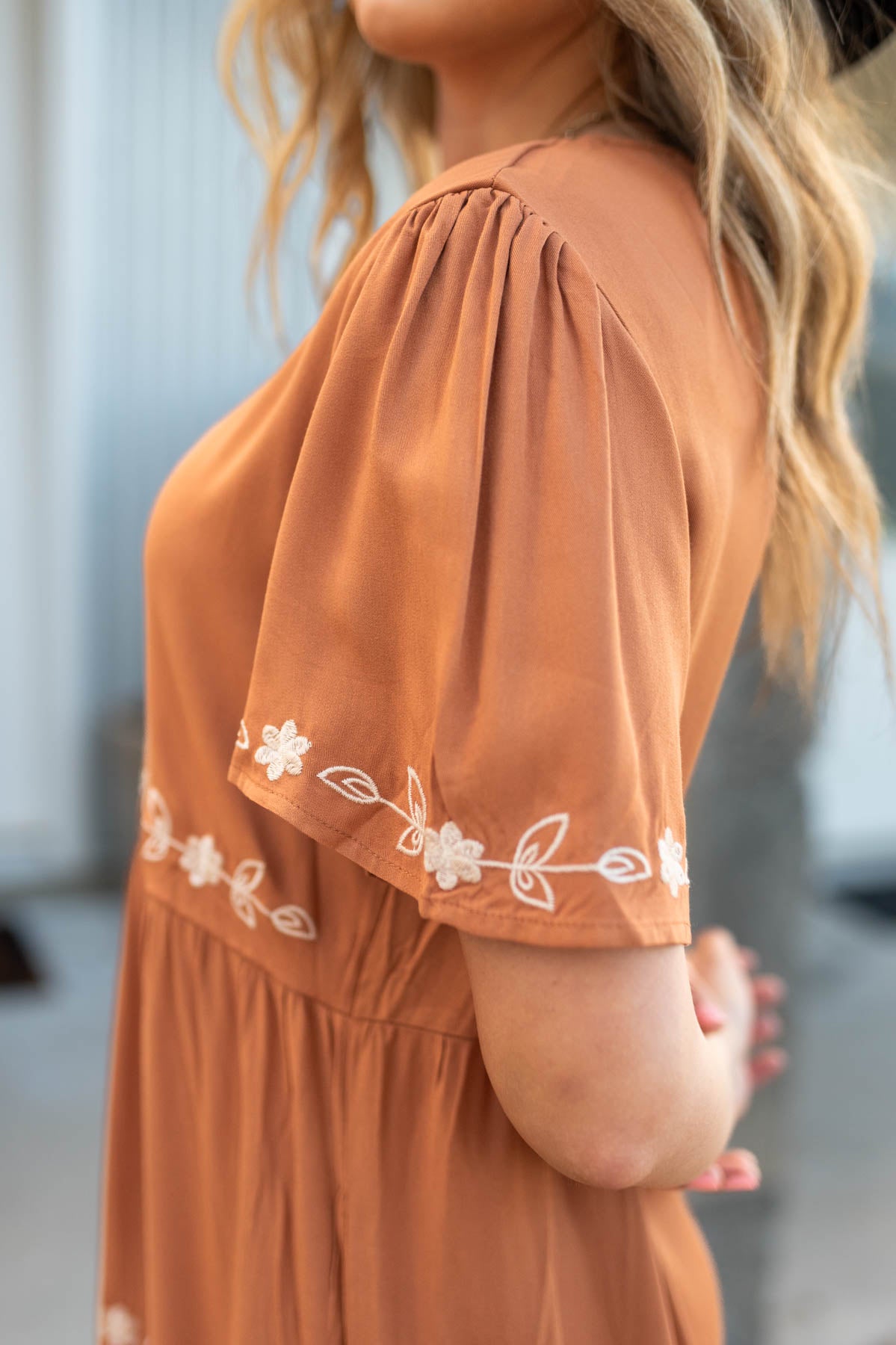 Sleeve view of a caramel dress with ivory embroidery
