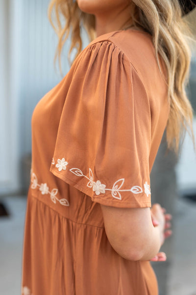 Sleeve view of a caramel dress with ivory embroidery