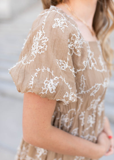 Close up of the sleeve and fabric on the  light mocha embroidered dress