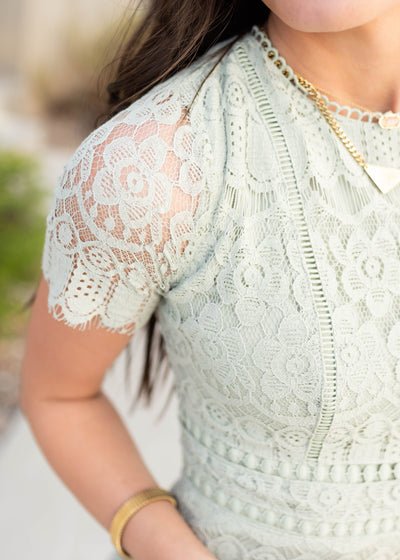 Close up of the fabric and sleeve on the light sage lace dress