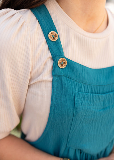 Close up of the buttons and pocket on the tiered teal overall dress