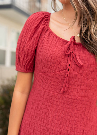 Close up of the fabric and bow at the neckline on the burgundy textured dress
