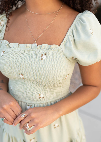 Close up of fabric and smocked bodice on the olive puff sleeve dress