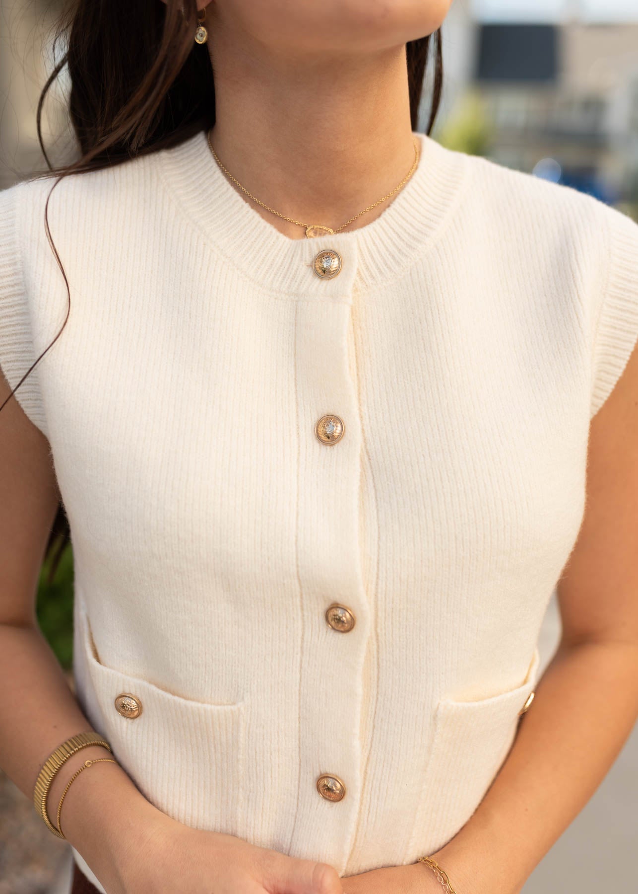 Close up of the metal buttons on the ivory sweater vest