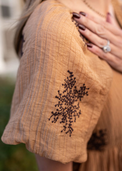 Close up of the fabric and sleeve on the tan embroidered dress