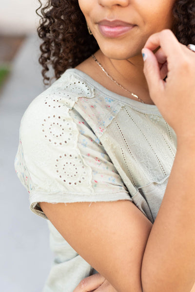 Close up of the eyelet fabric and sleeve of the moss green floral top