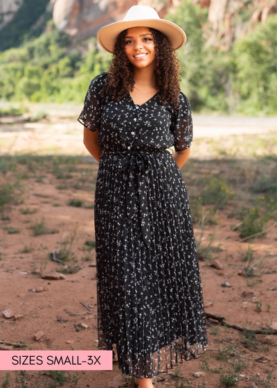 Short sleeve button bodice black floral dress that ties at the waist and has a pleated skirt