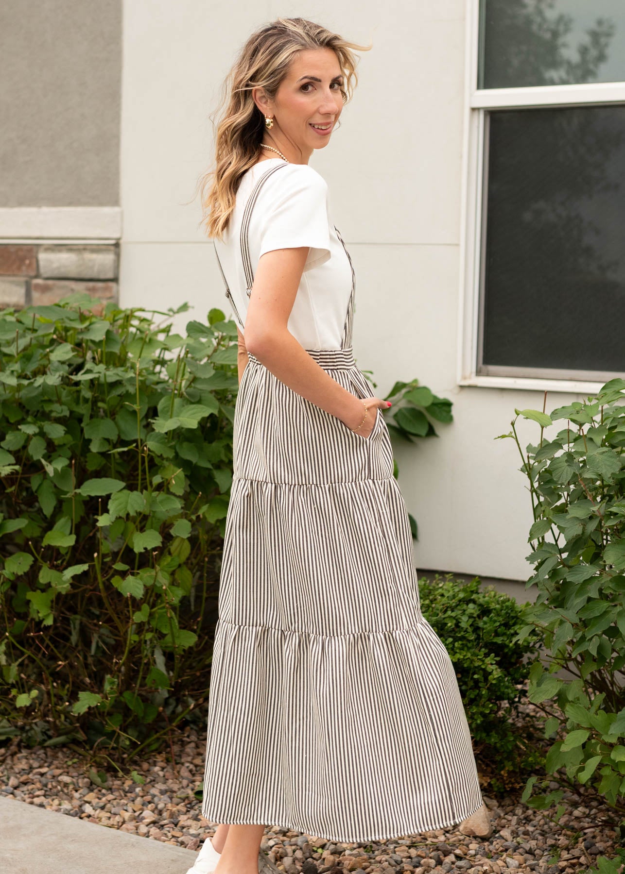 Side view of the charcoal stripe overall dress with pockets and a tiered skirt sold at Lena Layne