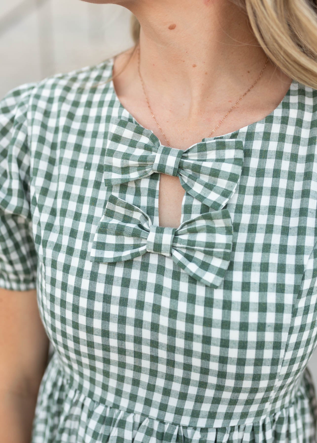 Close up of the bows and the fabric on the sage gingham ow dress