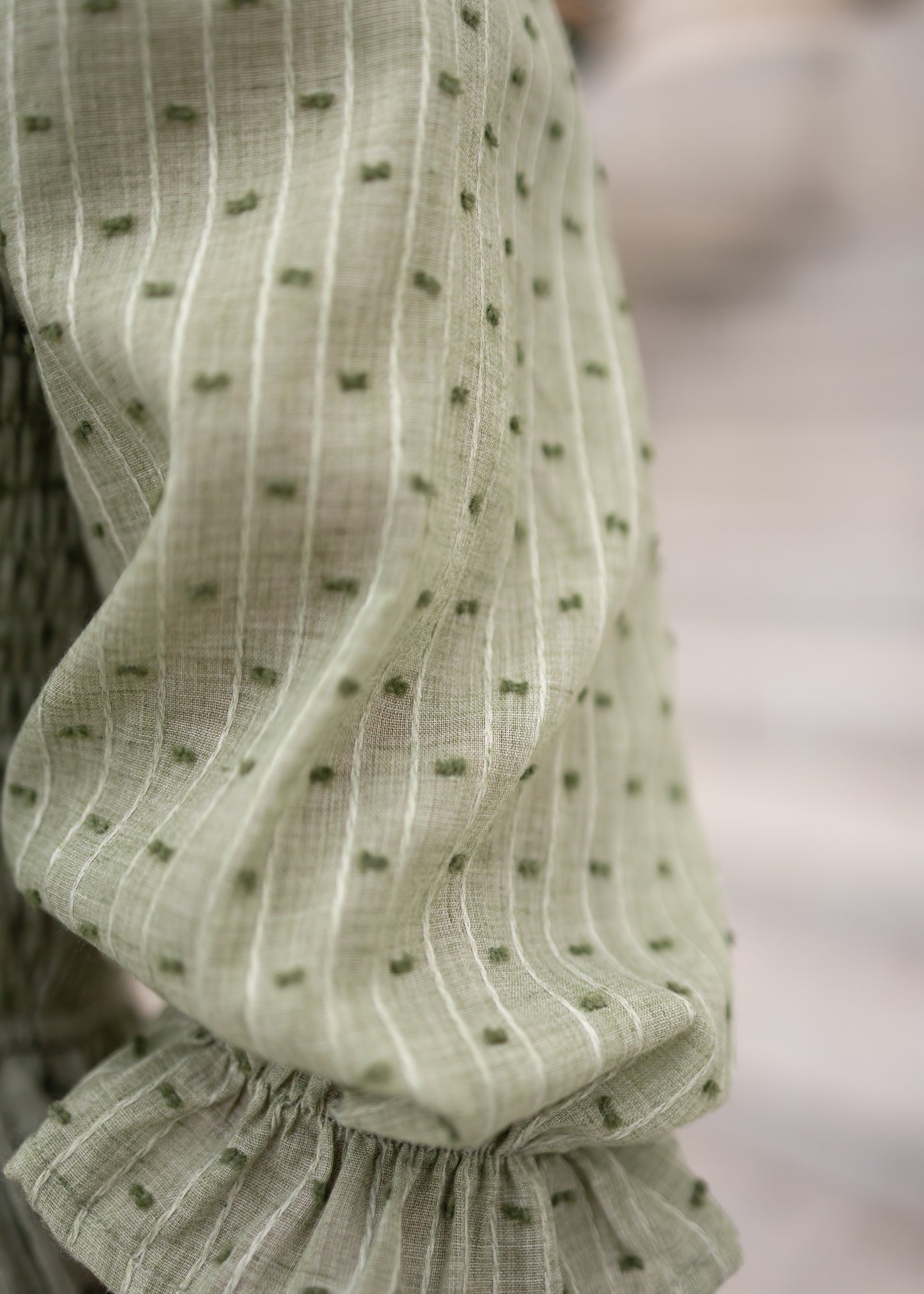 Close up of the fabric with small green dots on the green smocked dress 