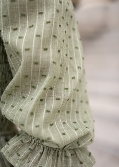 Close up of the fabric with small green dots on the green smocked dress 