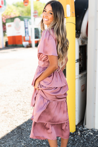 Side view of a mauve ruffle dress with short sleeves and elastic at the waist.