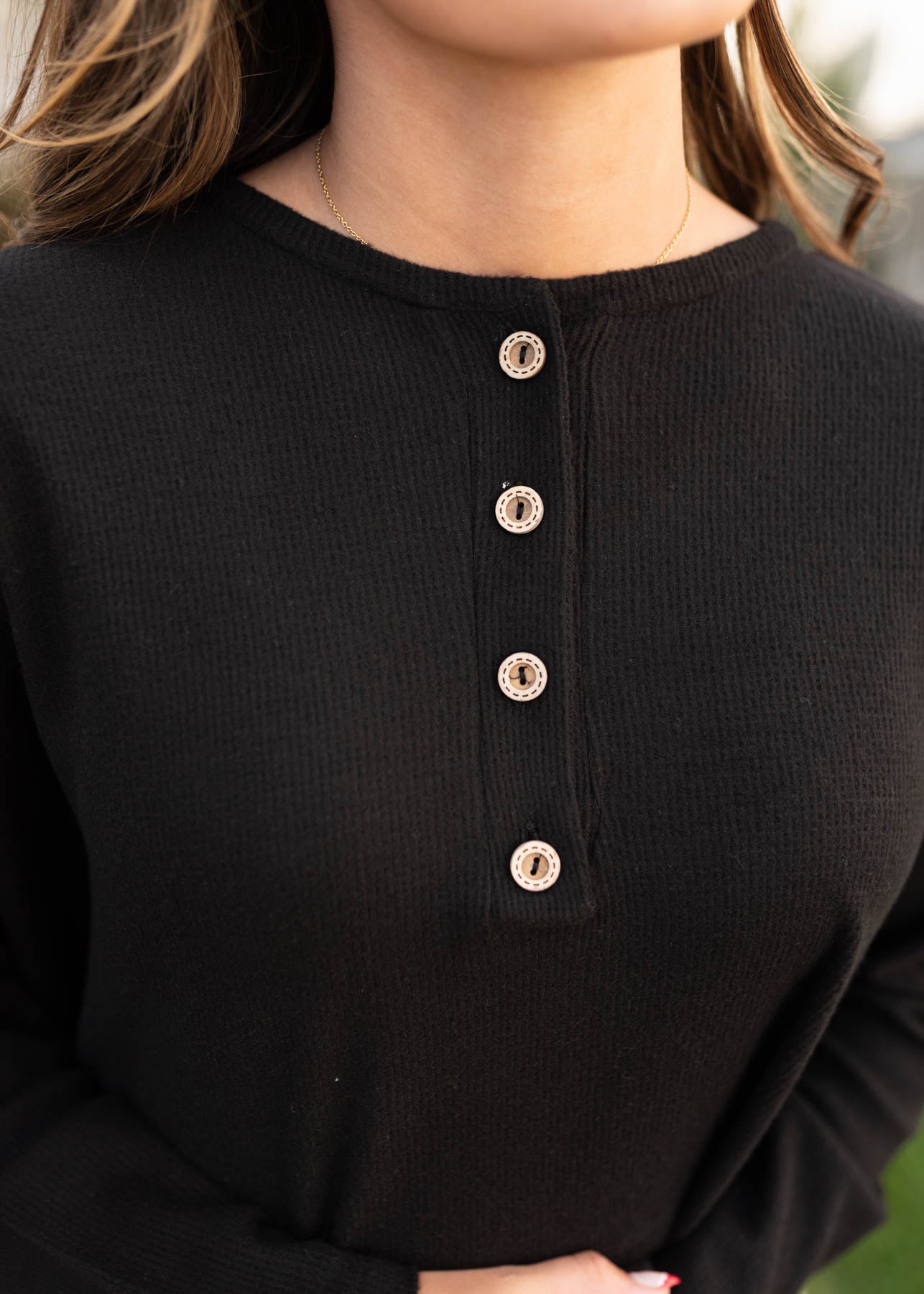 Close up of the button on the black textured top at Lena Layne
