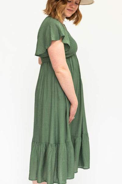 Side view of a short sleeve buttercream dress with a V-neck and smocked bodice.
