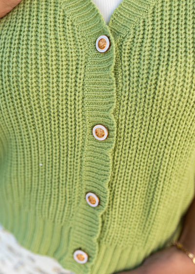 Close up of the buttons and knit pattern on the green vutton up vest