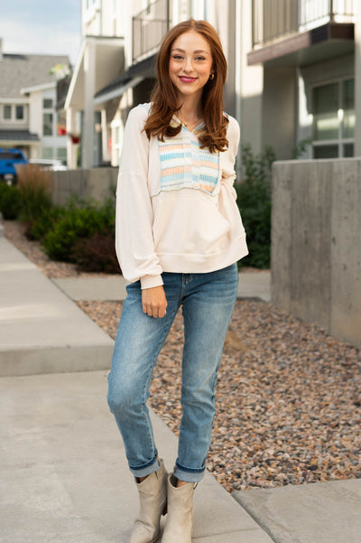 Oatmeal top with hoodie, long sleeves and pastel stripe pattern on the front