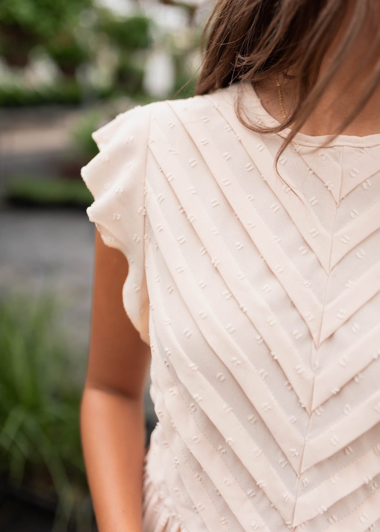 Close up of the pleats on the bodice of the beige swiss dot dress
