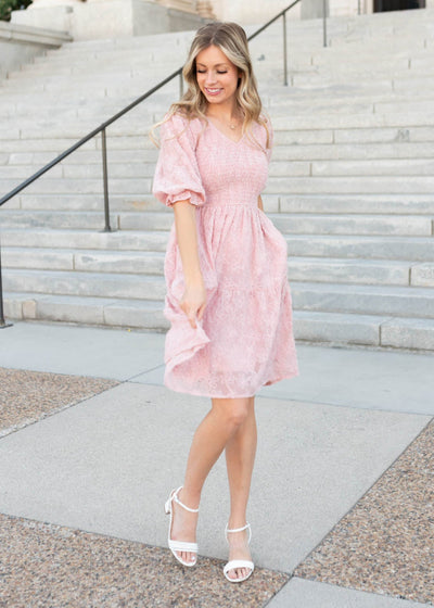 Tiered skirt on the blush floral textured dress with a smocked bodice and short sleeves by Lena & Lou at Lena Lyane