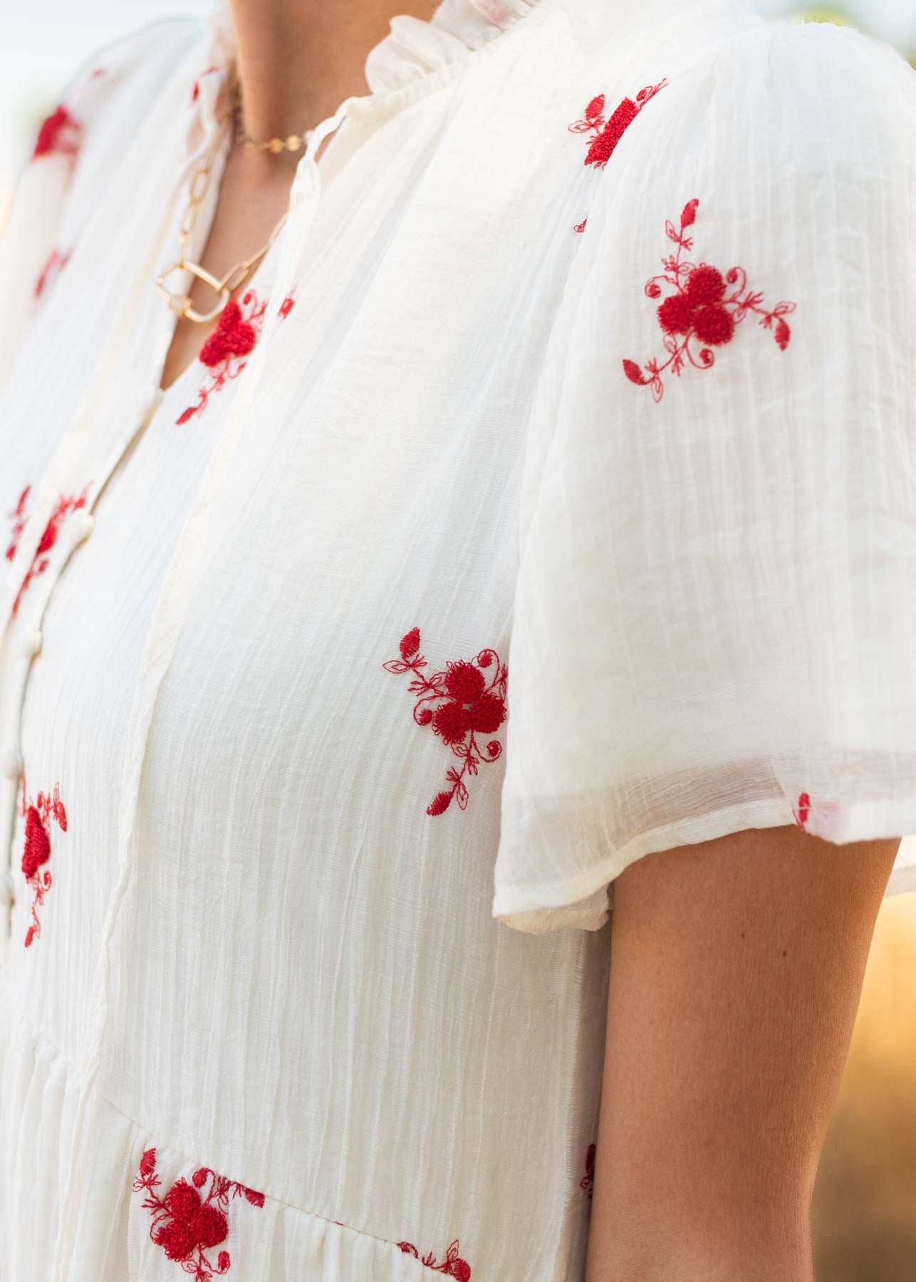 Close up of the sleeve and red flowers on the ivory floral dress