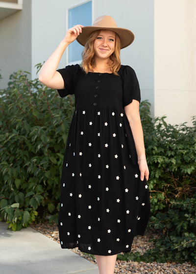 Short sleeve black dress with buttons on the bodice and small white flowers on the skirt