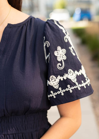 Close up of the embroidery on the sleeve of the navy embroidered dress