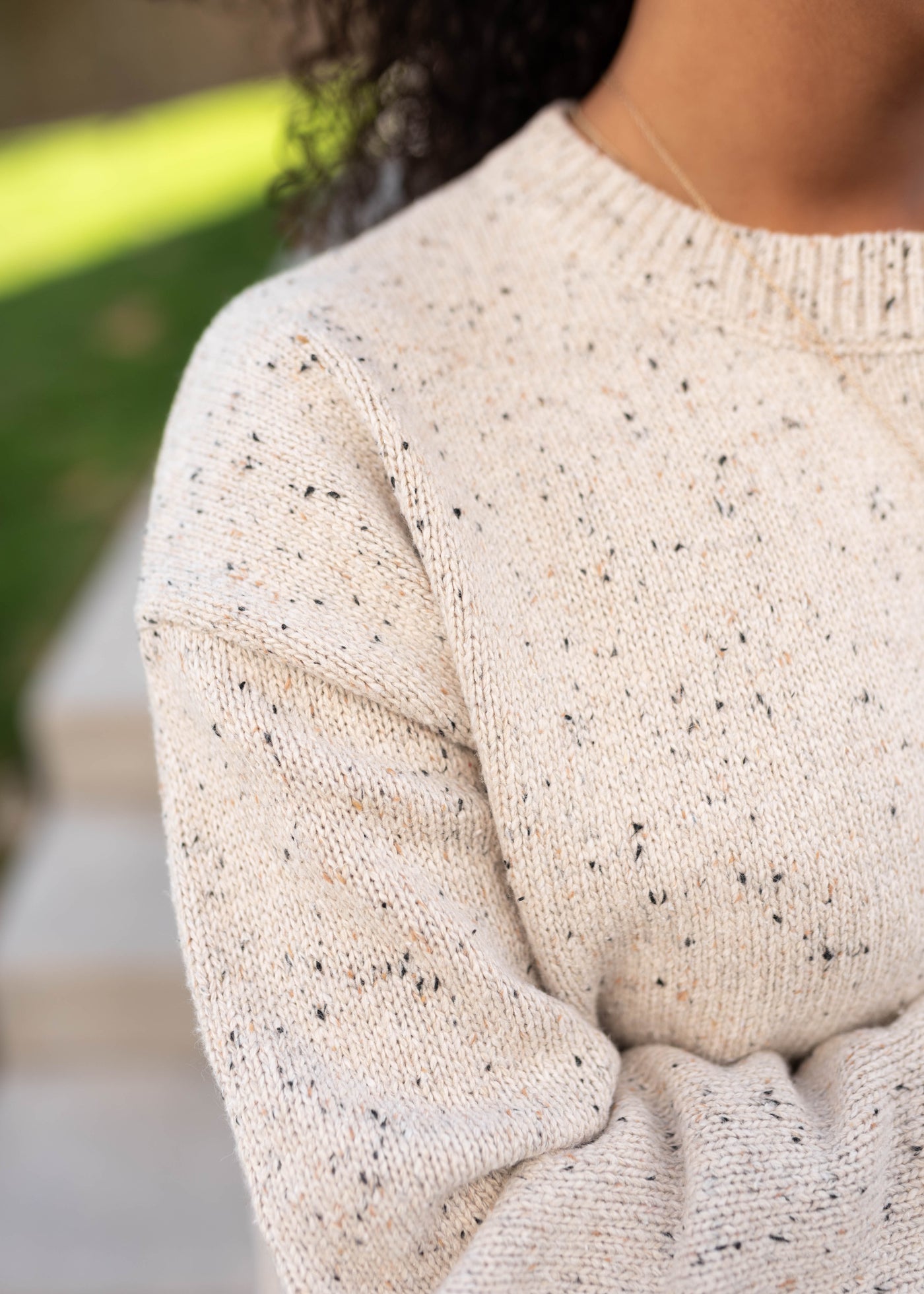 Close up of the sweater fabric and drop sleeve of the speckled taupe knit sweater