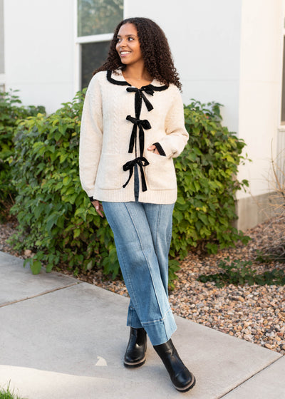 Trendy cream bow cardigan with long sleeves and front pockets