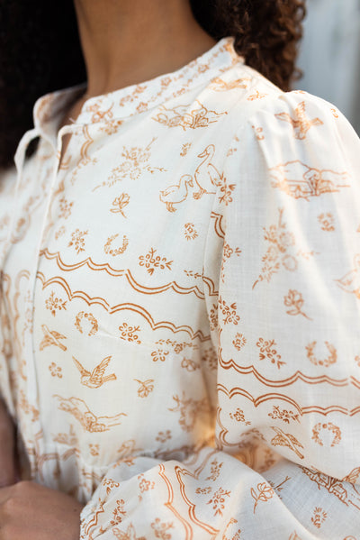 Close up of the dark tan patten on the cream patterned dress