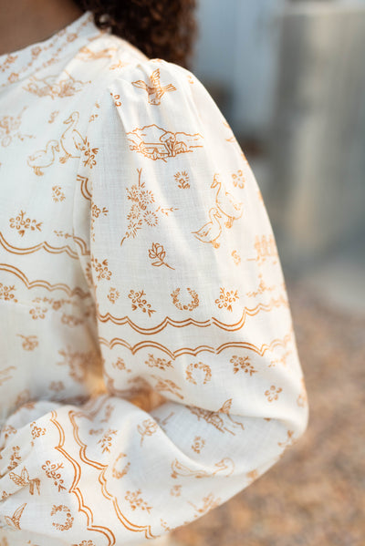 Close up of the the sleeve and fabric on the cream pattern dress
