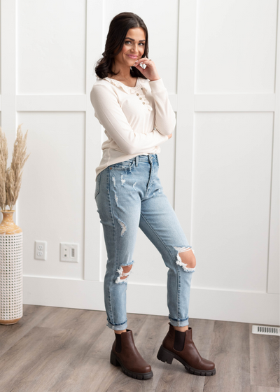 Long sleeve cream knit top with a ruffle along the buttons and neck