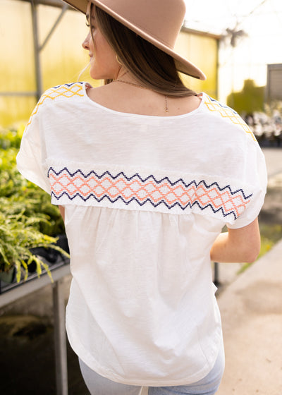 Back view of a white top with cross stitching on the back
