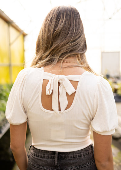 Back view of a ivory bodysuit that ties in the back